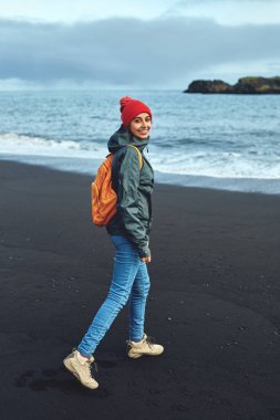 Kirkjufjara siyah kum plaj, Güney İzlanda üzerinde yürüyen kadın.