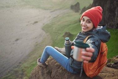 bir dağın tepesinde siting ve günbatımı İzlanda'zevk sırt çantası ile kadın uzun yürüyüşe çıkan kimse