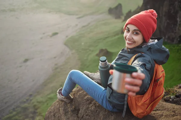 Randonneuse avec sac à dos assis au sommet d'une montagne et profitant du coucher de soleil en Islande — Photo