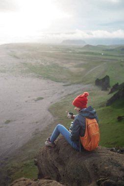 bir dağın tepesinde siting ve günbatımı İzlanda'zevk sırt çantası ile kadın uzun yürüyüşe çıkan kimse