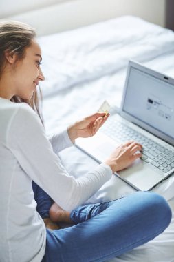 laptop ve kredi kartı olan bir genç gülümseyen kadın