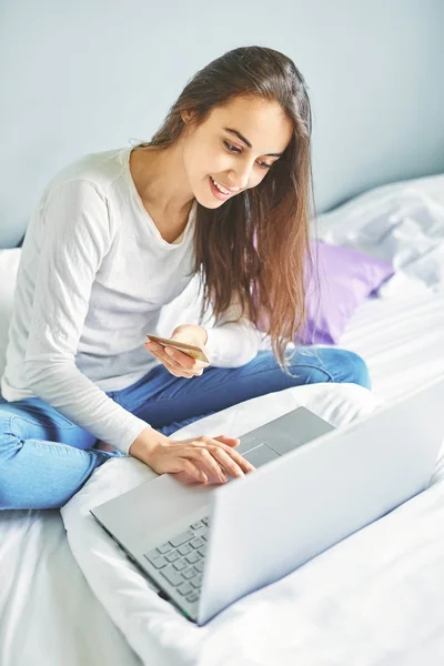 Nuori hymyilevä nainen kannettavan tietokoneen ja luottokortin kanssa — kuvapankkivalokuva