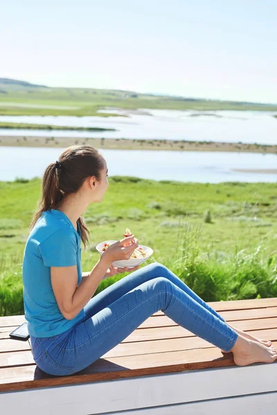Ung kvinna äter frukost på terrassen — Stockfoto