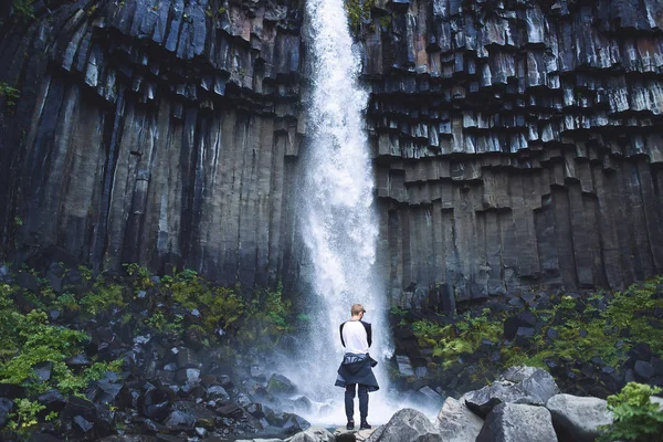 Homme sur le fond de la cascade de Svartifoss entouré de colonnes de basalte dans le sud de l'Islande — Photo