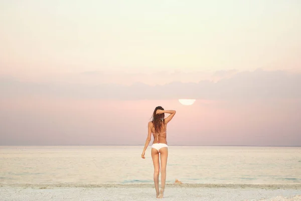 Kaunis seksuaalinen nainen merta ja auringonlaskua vastaan — kuvapankkivalokuva