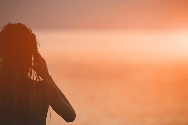 Силует красивої дівчини проти моря і заходу сонця — стокове фото