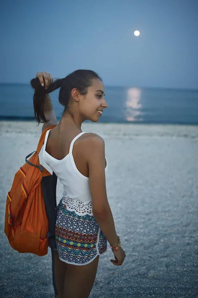 美丽的女人站在沙滩上, 看着日落时的大海 — 图库照片