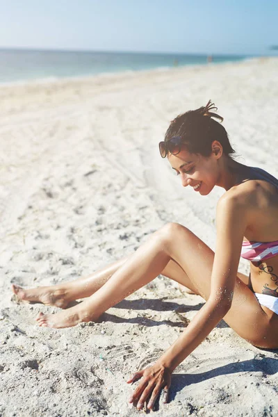 Mooie seksuele vrouw in bikini zit op de san op strand — Stockfoto