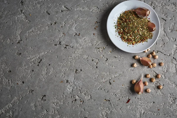 Een plaat van specerijen, kikkererwten en knoflook op de grijze betonnen achtergrond — Stockfoto