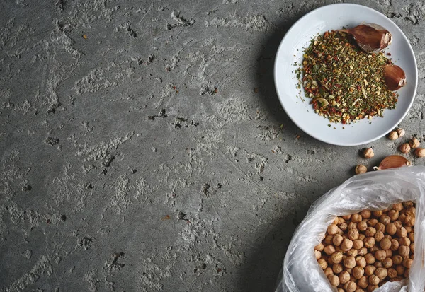 a plate of spices, chickpea and garlic on the grey concrete backdrop