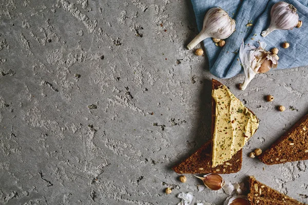Volkoren brood, kikkererwten en knoflook gesneden op de grijze betonnen achtergrond — Stockfoto