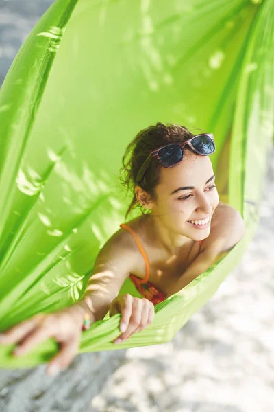 Ung lykkelig kvinne i en hengekøye på stranden – stockfoto