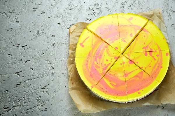 Gesneden mousse cake met geel rood glazuur op de grijze betonnen achtergrond — Stockfoto