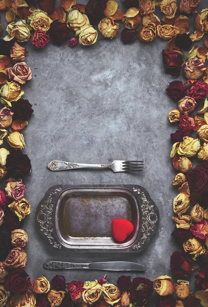Vintage metalen schotel in frame van gedroogde rozen toppen op de grijze betonnen achtergrond — Stockfoto