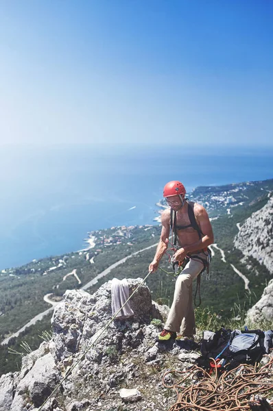 Adam kaya tırmanışçısı uçurumun tepesinde duruyor — Stok fotoğraf