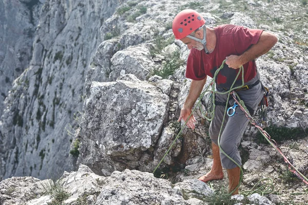 Adam kaya tırmanışçısı uçurumun tepesinde duruyor ve bir ortak belays — Stok fotoğraf