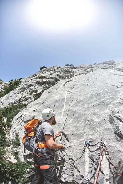 Dağcı bir kayanın üzerinde bir çıkıntı üzerinde duruyor ve ortak belays — Stok fotoğraf