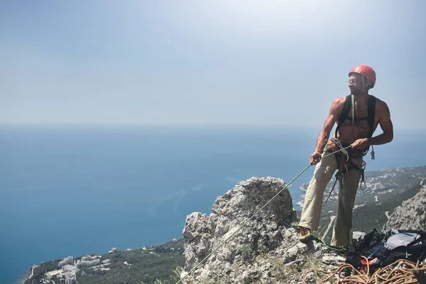 Adam kaya tırmanışçısı uçurumun tepesinde duruyor — Stok fotoğraf