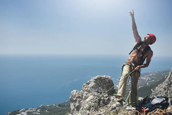 Hombre escalador de roca se encuentra en la cima del acantilado — Foto de Stock