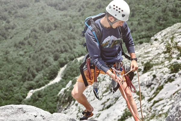 Man rock klättrare på toppen av klippan och belays en partner — Stockfoto