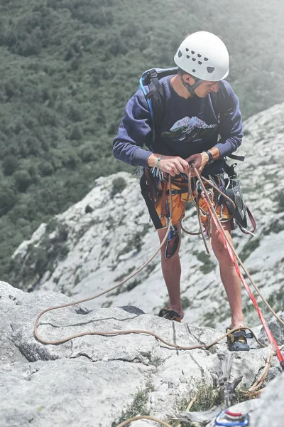 Man rock klättrare på toppen av klippan och belays en partner — Stockfoto