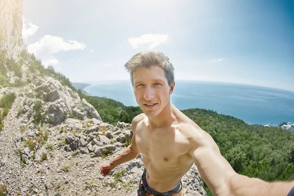 Urheilullinen mies kiipeilijä tekee selfie vuoret ja meri tausta — kuvapankkivalokuva