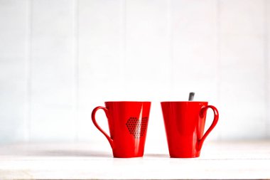 iki kırmızı kahve bardağı beyaz masanın üzerine yazdırılan yürekleri