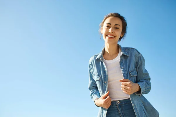 Retrato de uma jovem mulher atraente no fundo do céu azul — Fotografia de Stock