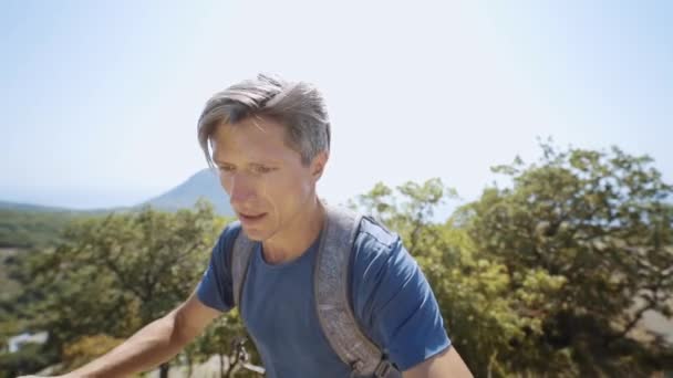 Nahaufnahme Weitwinkel-Selfie-Porträt eines jungen erwachsenen Mannes, der an einem Sommertag auf einem Bergrücken läuft. — Stockvideo