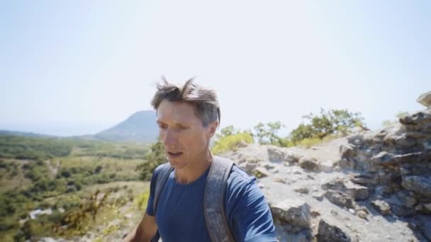 Closeup wide angle slow motion selfie portrait of young adult man trail runner running on mountain ridge at summer day. — Stock Video