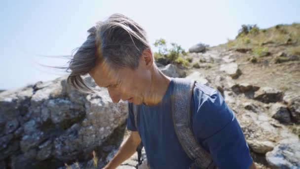 Closeup wide angle slow motion selfie portrait of young adult man trail runner running on mountain ridge at summer day. — Stock Video