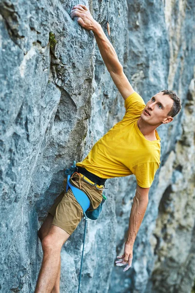 Young strong man climbing challenging route on a high vertical limestone cliff. — Stock Photo, Image