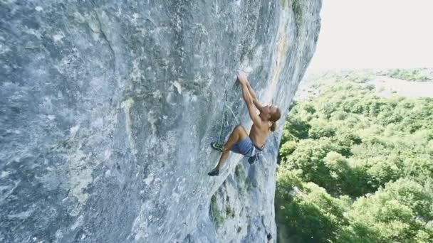 Uomo forte arrampicatore di roccia muscolare al rallentatore salendo dinamicamente su una scogliera verticale, facendo movimenti larghi e stringendo forte . — Video Stock