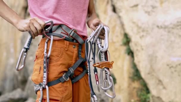 Detalhe de escalada de trepadeira mulher chicote com engrenagem e mãos anexando quickdraw no arnês , — Vídeo de Stock