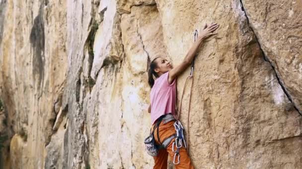 Mujer en forma joven escalador escalando montaña arriba, buscando, alcanzando y agarrando bodega — Vídeo de stock