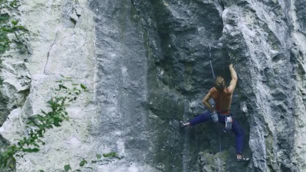 Vista posterior fuerte musculoso hombre escalador escalada en la ruta deportiva al aire libre en un acantilado vertical — Vídeo de stock