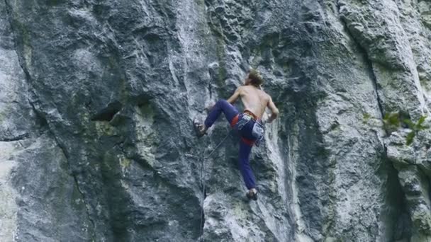 Vista posterior fuerte musculoso hombre escalador escalada en la ruta deportiva al aire libre en un acantilado vertical — Vídeos de Stock