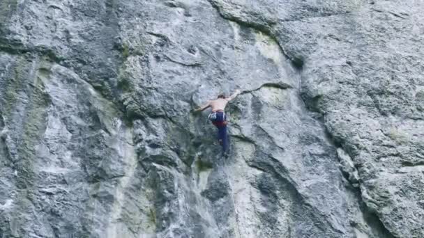 Назад вид сильного мускулистого человека скалолазания по спортивному маршруту на открытом воздухе на вертикальной скале — стоковое видео