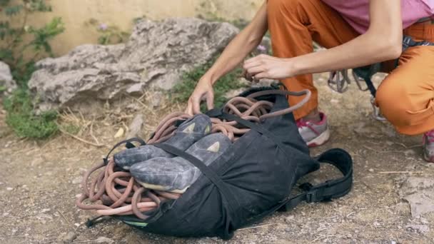 ロッククライミングの詳細。女性は登山用具のバックパックからクライミング用具を取り出します。120fpsのスローモーション — ストック動画