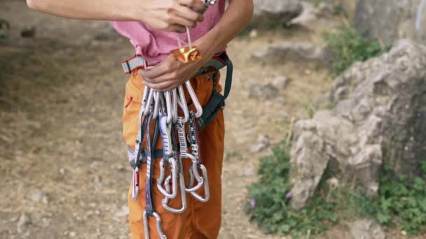 Details zum Klettern. Bergsteigerin zieht Sicherungsvorrichtung aus Gurtzeug und gibt jemandem, der gerade klettern will. — Stockvideo