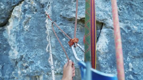 Climbing gear closeup POV. First person view of belayers hand with belaying device attached to rope, several ropes on which a person hangs — Stock Video