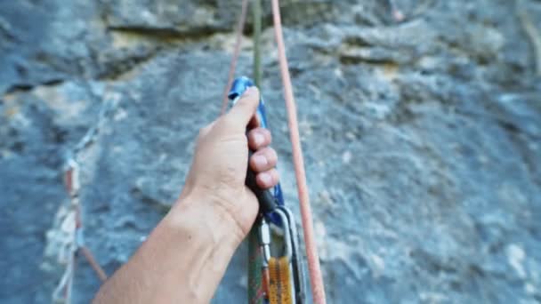 Klimuitrusting close-up Pov. Eerste persoon weergave van make hand met opklimmer apparaat bevestigd aan touw, verschillende touwen waaraan een persoon hangt — Stockvideo
