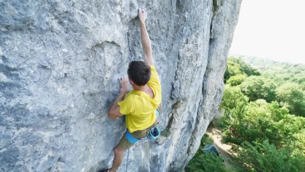 Proporcionar vista angular del hombre escalador de roca en camiseta amarilla, escalada en un acantilado, la búsqueda, el alcance y agarre bodega. al aire libre escalada en roca y concepto de estilo de vida activo — Vídeos de Stock