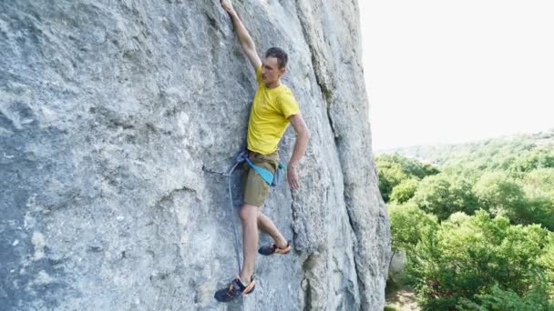 Вид на скелелазну людину в жовтій футболці, сходження на скелю, на жорсткий спортивний маршрут, відпочинок і рукостискання. на відкритому повітрі скелелазіння та концепція активного способу життя — стокове відео