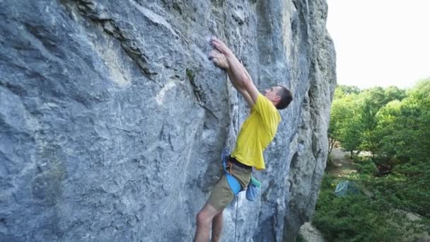 Proporcionar vista angular del hombre escalador de roca en camiseta amarilla, escalada en un acantilado, la búsqueda, el alcance y agarre bodega. al aire libre escalada en roca y concepto de estilo de vida activo — Vídeos de Stock