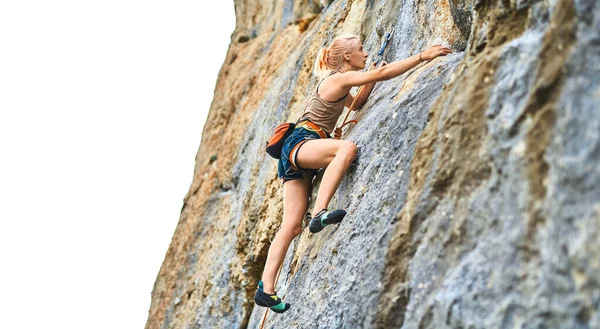 Молода жінка скелелазіння намагається піднятися на скелю, шукаючи, досягаючи і захоплюючи тримаючись . — стокове фото