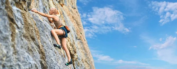 Junge athletische Bergsteigerin klettert an der Klippe — Stockfoto