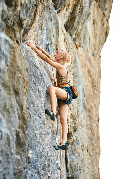 Genç atletik kadın kaya tırmanışçısı uçuruma tırmanıyor. — Stok fotoğraf