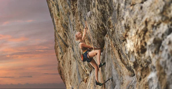若い運動選手のロッククライマーが崖の上に登り — ストック写真