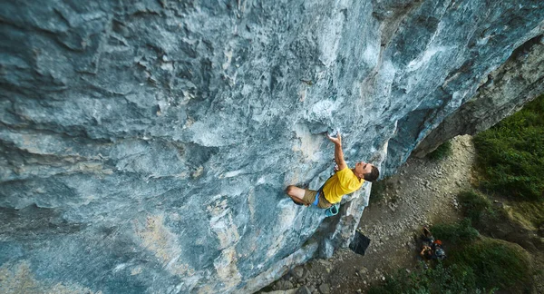 Vista superior do homem escalador de rocha em t-shirt amarela, subindo em um penhasco — Fotografia de Stock